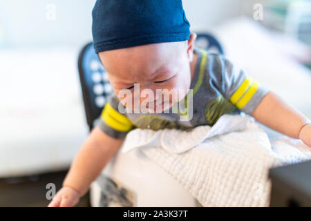 Triste bimbo seduto e pianto. Il bambino è di 4 mesi di età Foto Stock