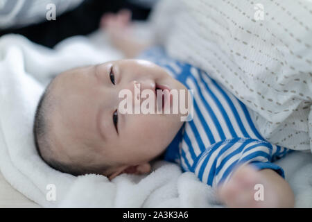 Adorabili e sorridente bambino sdraiato sul letto prima di dormire. Il bambino è di 4 mesi di età Foto Stock