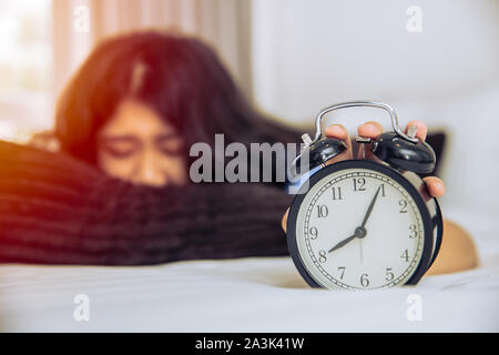 Assonnato lazy Asian teen girl ancora a letto svegliarsi tardi canto muto sveglia mattina tempo Foto Stock