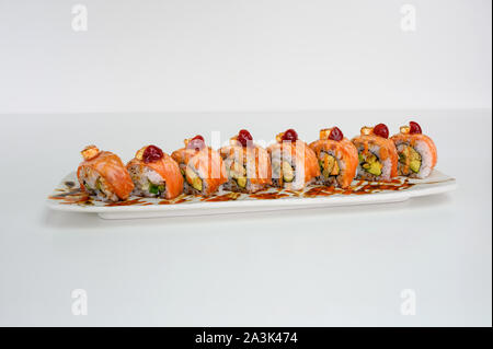 Salmone affumicato riempito di avocado, kani, tamago, cetriolo sottaceto sushi il rotolo con la crema di formaggio sulla piastra bianca Foto Stock