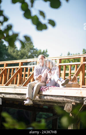 Giovane seduto sul ponte mentre avente picnic Foto Stock