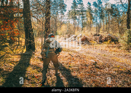 Unidentified ri-enactor vestito come soldato di Stati Uniti d'America Fanteria di II Guerra Mondiale nascosto in esecuzione con pistole mitragliatrici nella foresta a Histo Foto Stock