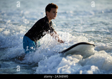 Surfer battaglie le onde su una bella giornata di sole Foto Stock