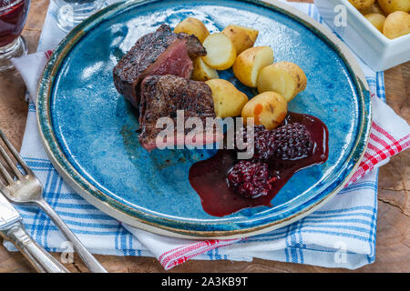 In padella la carne di cervo con salsa di blackberry e bollite patate baby Foto Stock