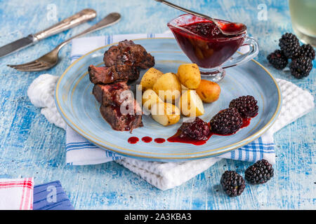 In padella la carne di cervo con salsa di blackberry e bollite patate baby Foto Stock