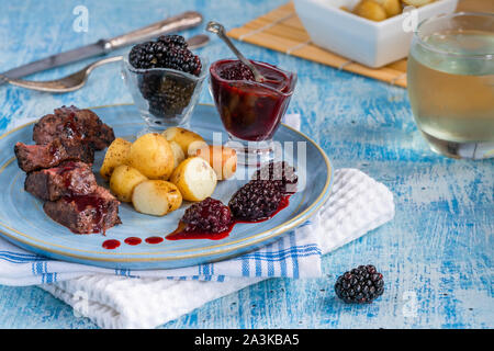 In padella la carne di cervo con salsa di blackberry e bollite patate baby Foto Stock