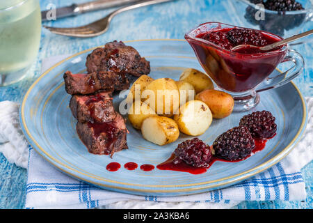 In padella la carne di cervo con salsa di blackberry e bollite patate baby Foto Stock