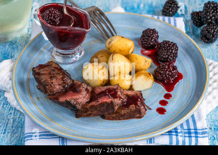 In padella la carne di cervo con salsa di blackberry e bollite patate baby Foto Stock