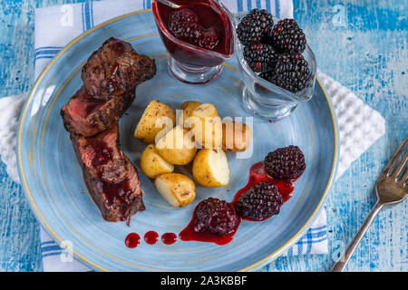 In padella la carne di cervo con salsa di blackberry e bolliti baby .patate Foto Stock