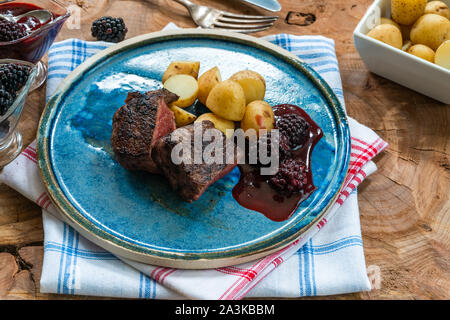 In padella la carne di cervo con salsa di blackberry e bollite patate baby Foto Stock