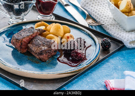 In padella la carne di cervo con salsa di blackberry e bollite patate baby Foto Stock