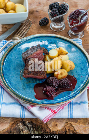 In padella la carne di cervo con salsa di blackberry e bollite patate baby Foto Stock