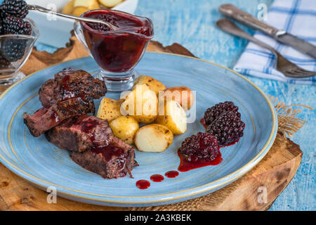 In padella la carne di cervo con salsa di blackberry e bollite patate baby Foto Stock