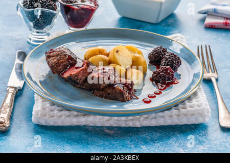 In padella la carne di cervo con salsa di blackberry e bollite patate baby Foto Stock