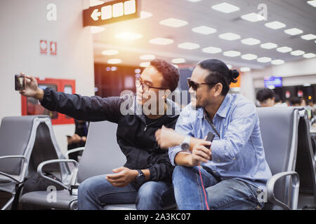 Uomo asiatico con zaino traveler utilizzando la smart telefono cellulare per la video chiamata e prendendo la foto di un aeroporto,sfocata e soft focus Foto Stock