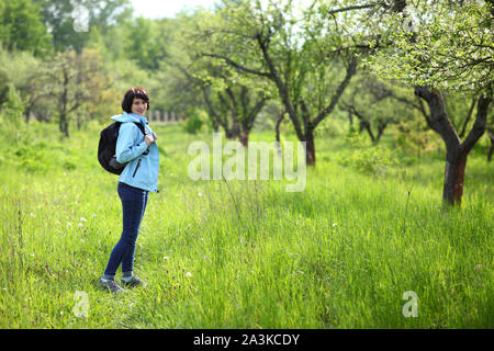 Una ragazza raccoglie snowdrops nella foresta. Bella giovane donna bagna i raggi del sole di primavera in una radura della foresta. Foto Stock