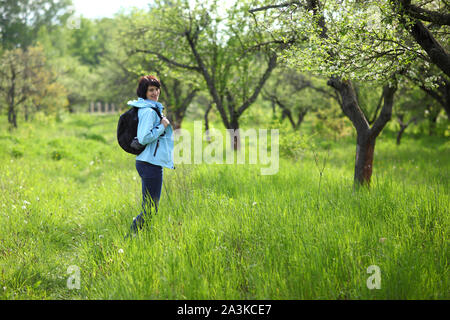 Una ragazza raccoglie snowdrops nella foresta. Bella giovane donna bagna i raggi del sole di primavera in una radura della foresta. Foto Stock