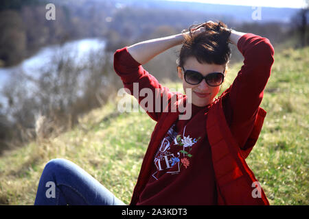 Una ragazza raccoglie snowdrops nella foresta. Bella giovane donna bagna i raggi del sole di primavera in una radura della foresta. Foto Stock