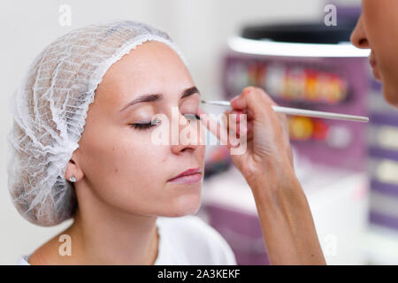 La cosmetologia client cabinet seduto sul divano. Estetista si applica la marcatura sulla sopracciglia. Preparazione per la procedura del sopracciglio permanente del trucco. Free s Foto Stock