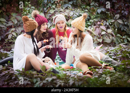 Giovani donne bere vino brulé nell'autunno del parco. Soleggiata giornata autunnale. All'aperto lifestyle moda ritratto. Emozioni positive. Foto Stock