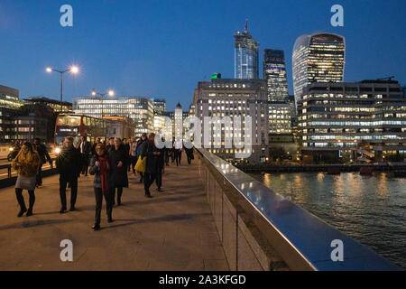 Pendolari su London Bridge al tramonto con il Coccio al di là, London, England, Regno Unito Foto Stock