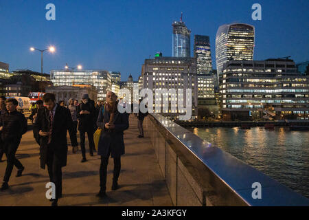 Pendolari su London Bridge al tramonto con il Coccio al di là, London, England, Regno Unito Foto Stock