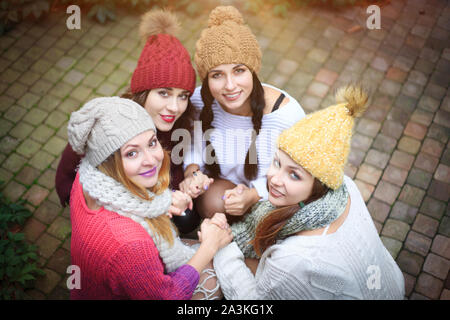 Le ragazze in maglia caldi abiti e cappelli abbraccio, vista dall'alto. Giornata autunnale, un gruppo di amici. Emozioni positive. Foto Stock