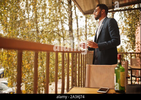 Bello e ben vestito uomo arabo di fumo di sigaro balcone di pub. Foto Stock