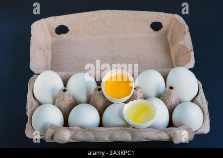 Le uova bianche e un uovo rotto in scatola di cartone con mockup al testo. La proteina naturale. Mangiare sano. Foto Stock