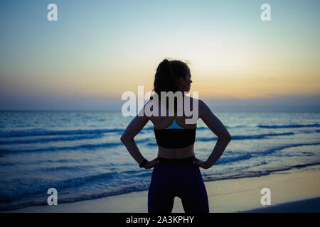 Silhouette di montare la donna nel mondo dello sport vestiti sulla Ocean Shore in serata rilassante dopo allenamento. Foto Stock