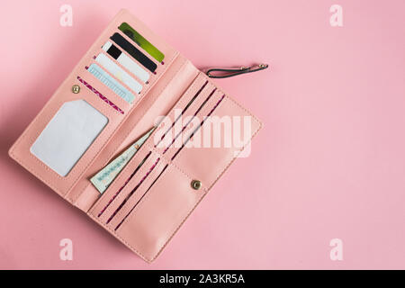 Aprire rosa femmina wallet. Lay piatto. Copia dello spazio. Contenuto della borsa di moda. Foto Stock