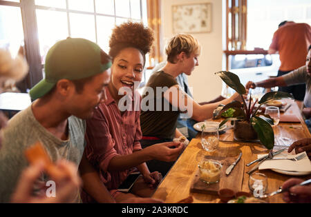 Gruppo sorridente di diversi amici parlando a pranzo insieme Foto Stock