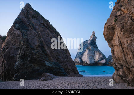 Epic Orsa Beach, Sintra, Portogallo. In salmì picchi di roccia in sera morbida luce del tramonto. Oceano atlantico paesaggio della costa Foto Stock