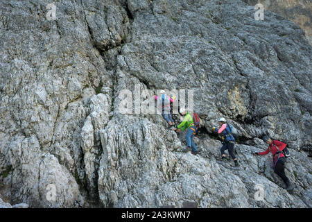 Una guida di montagna e diversi client salendo una Via ferrata nelle Dolomiti Italaian Foto Stock