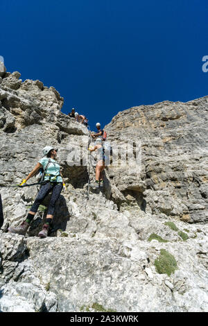 Una guida di montagna e diversi client salendo una Via ferrata nelle Dolomiti Italaian Foto Stock