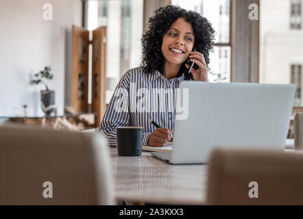 Donna sorridente imprenditore seduti a casa a parlare sul suo cellulare Foto Stock