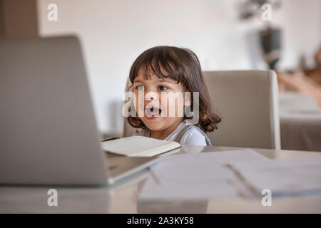 Ridere bambina guardare qualcosa sulla sua madre del laptop Foto Stock