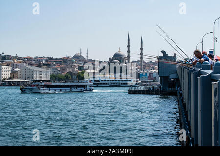 Istanbul: skyline della città e i pescatori locali con la loro canna da pesca sul Ponte di Galata, il ponte che attraversa il Golden Horn e il Bosforo Foto Stock