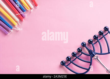 Immagine della festa ebraica Chanukkà candele colorate, menorah candelabri tradizionali su sfondo rosa.Flat lay.Copia spazio per il testo. Foto Stock