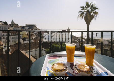 La prima colazione con Pasteis de Belem e il succo di arancia in open bar affacciato sul quartiere di Alfama e sul mare nel centro di Lisbona a Portas do Sol viewpoi Foto Stock