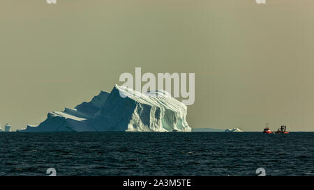 Un rosso barca da pesca nei pressi di iceberg in Discoteca Bay (Groenlandia) durante la stagione estiva Foto Stock