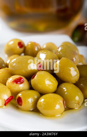 Ciotola di olive verdi ripiene di peperone rosso su sfondo bianco Foto Stock