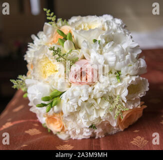 Bianco bouquet della sposa con fresia, rose e peonie, giacente sul letto Foto Stock