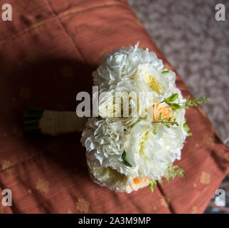 Bianco bouquet della sposa con fresia, rose e peonie, giacente sul letto Foto Stock
