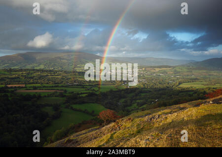 Rainbows oltre Crickhowell con il nero montagne in distanza. Parco Nazionale di Brecon Beacons. La contea di Powys. Il Galles. Regno Unito. Ottobre 2019 Foto Stock
