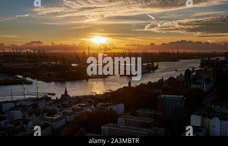 Immagine del porto di Amburgo al tramonto con una vista del fiume Elba e il giallo e il rosso di colore del cielo della sera Foto Stock