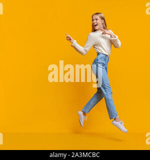 Ragazza giovane salti in aria e a puntare su uno spazio di copia Foto Stock