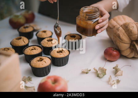 Il panettiere crea i tortini in stampi. Riempimento con biscotti fatti in casa caramello liquido. Foto Stock