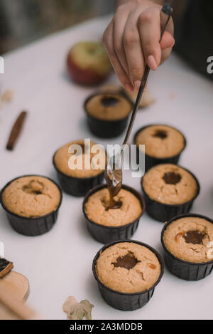 Il panettiere crea i tortini in stampi. Riempimento con biscotti fatti in casa caramello liquido. Foto Stock