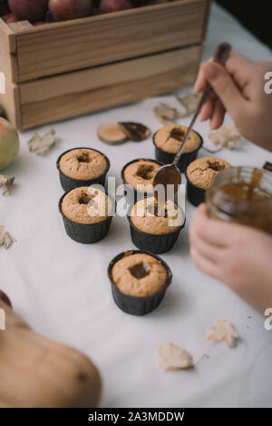 Il panettiere crea i tortini in stampi. Riempimento con biscotti fatti in casa caramello liquido. Foto Stock